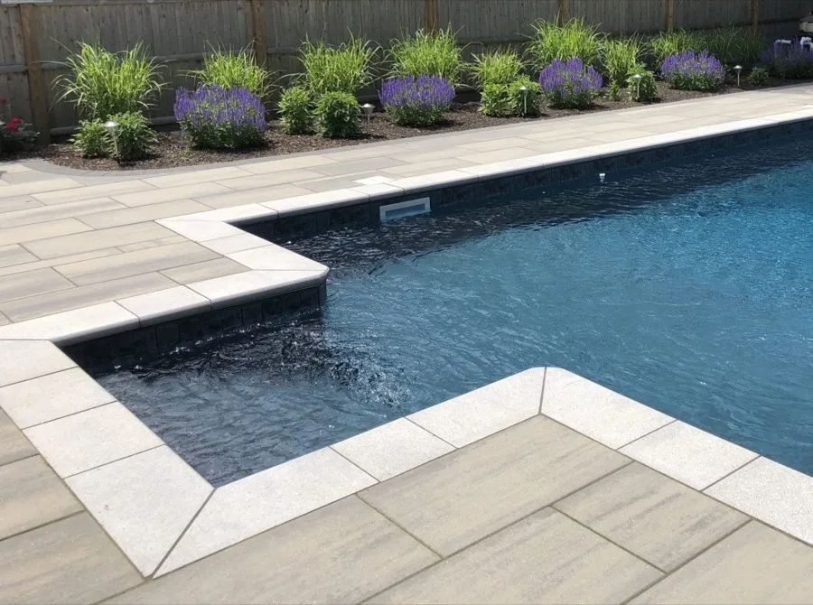Poolside paver patio with landscaped plantings
